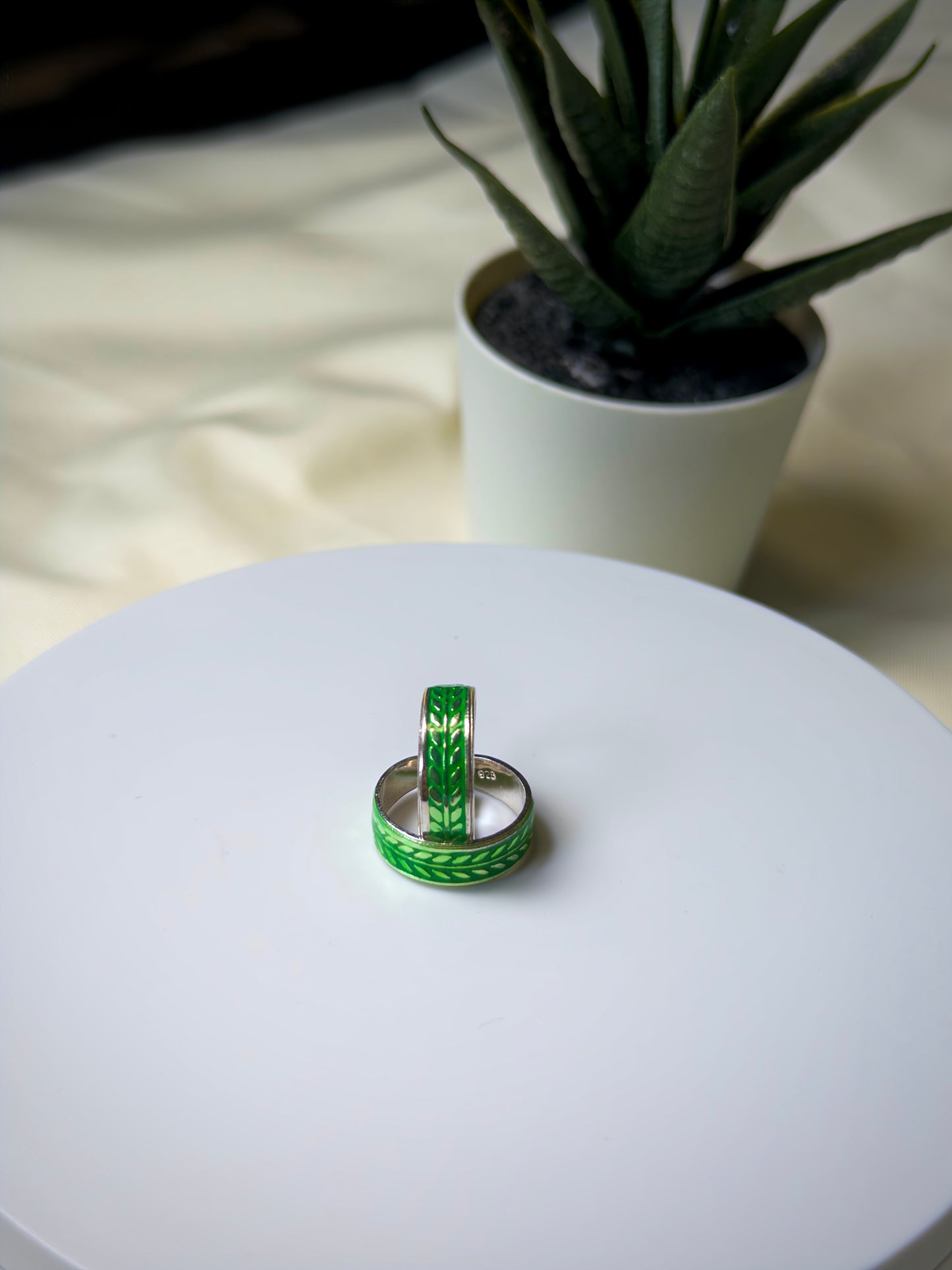Green Toe ring on a white surface with a plant in the background