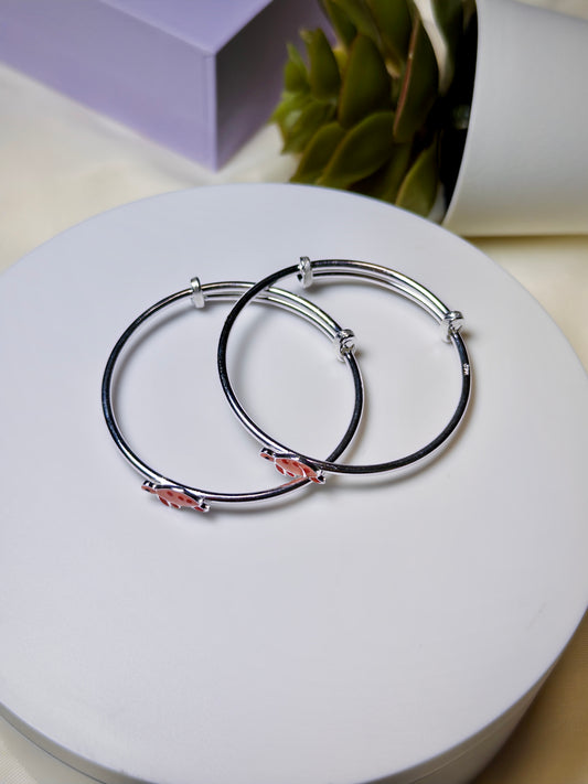 Silver baby kada with pink turtle on a white surface