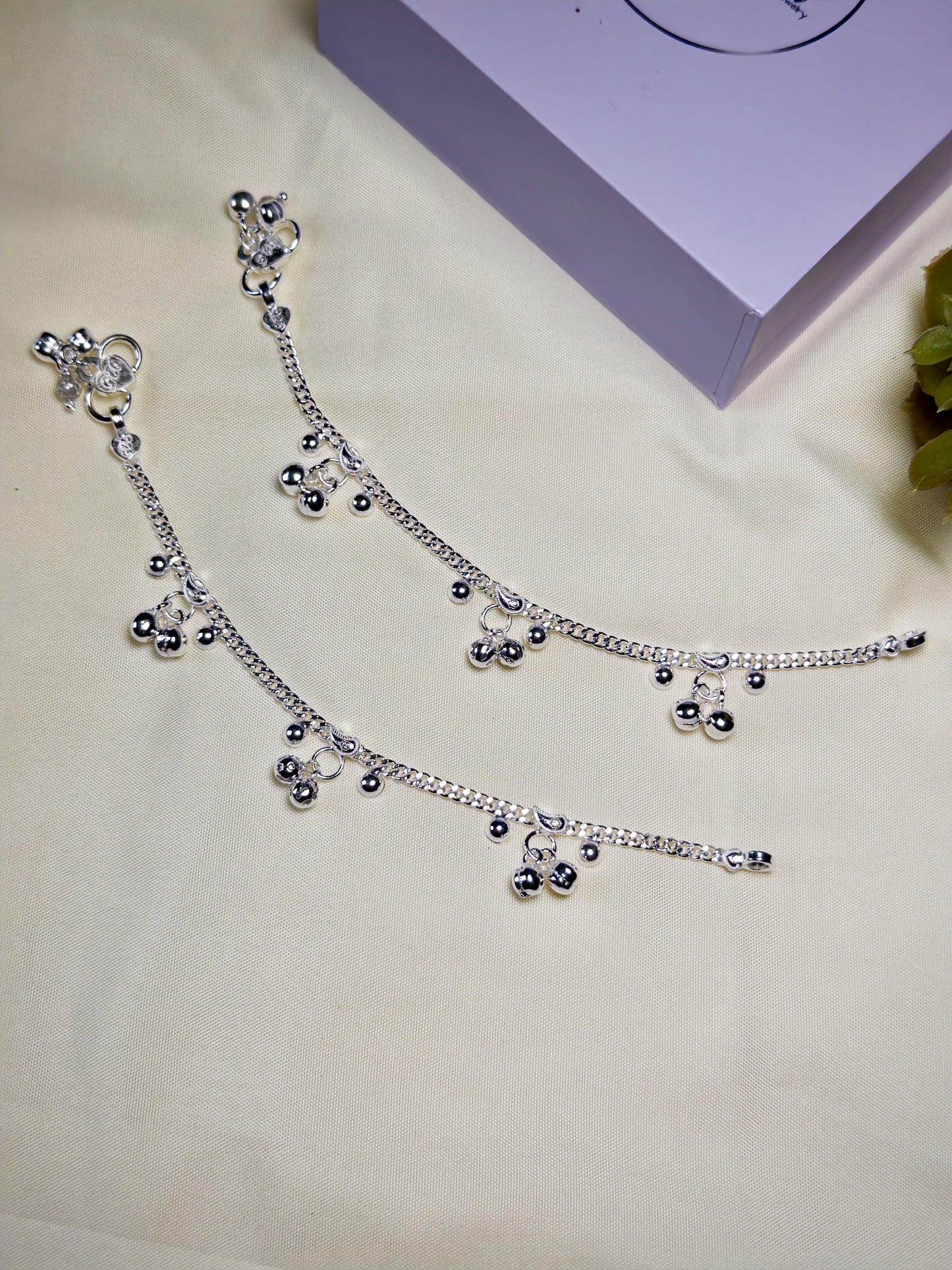 Kids silver anklets with charms on a light background