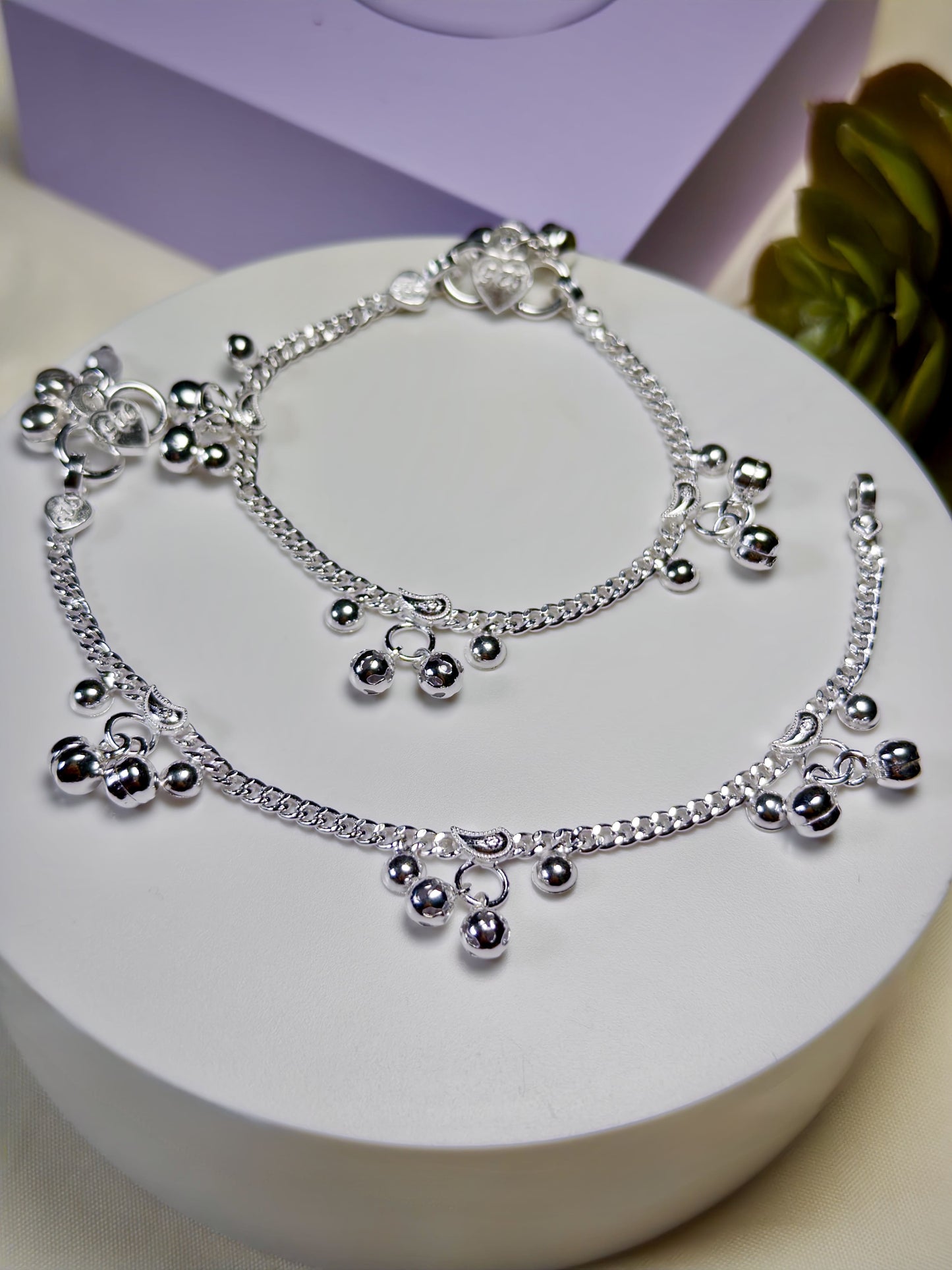Kids silver anklets with beads on a white surface