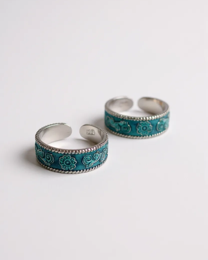 Pair of turquoise and silver toe rings on a light gray background