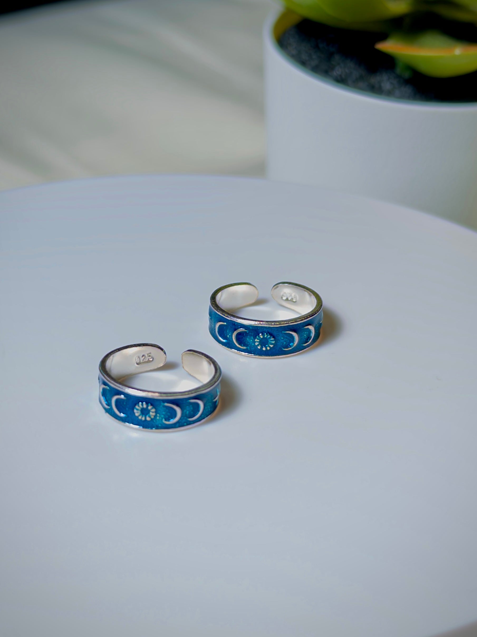 Pair of silver and blue toe rings on a light surface