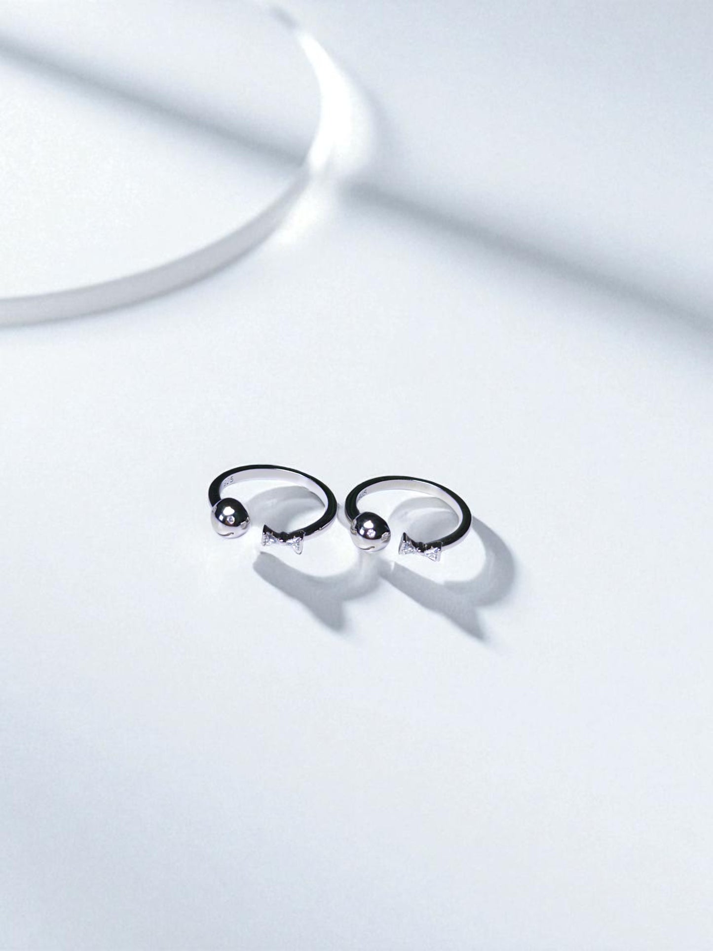 Pair of silver toe rings on a light gray background