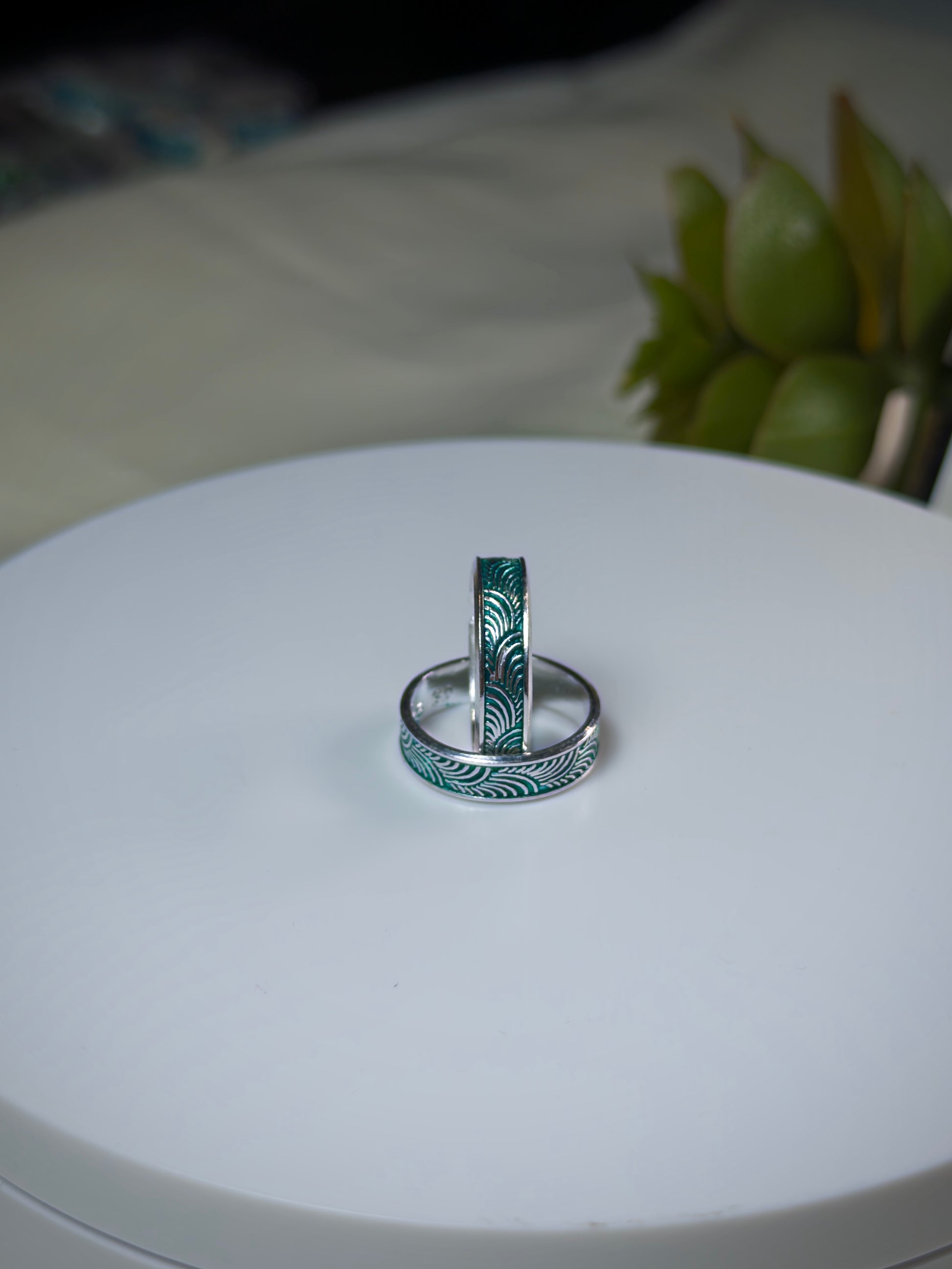 Two toe rings with feathered design on a white surface