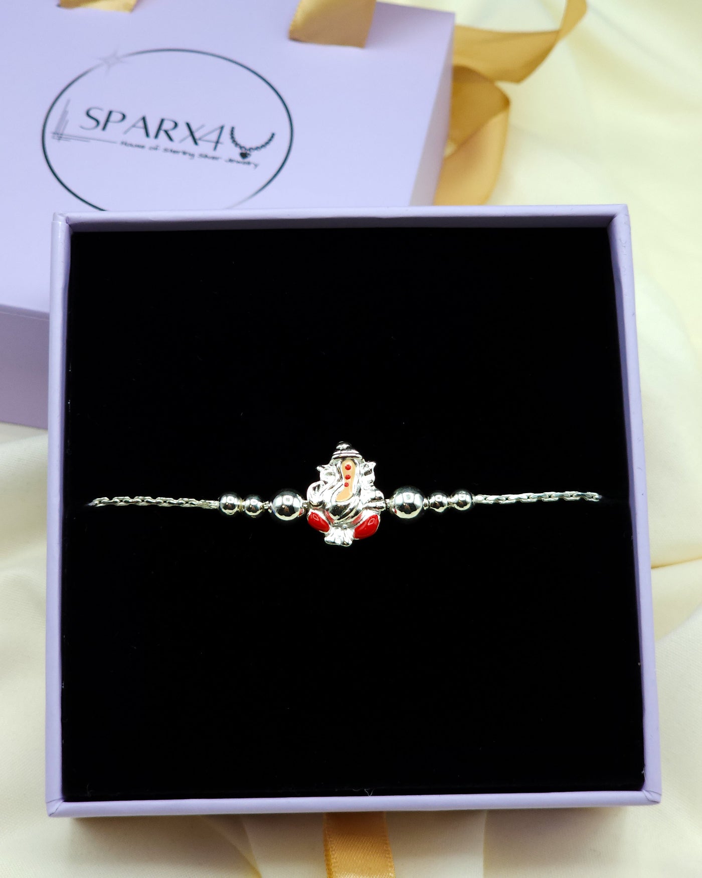 Silver bracelet with a red and silver Lord Ganesh charm in a black box