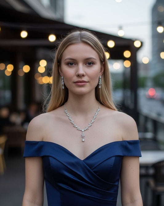 Woman wearing a blue off-shoulder dress with a silver jewelry set in an outdoor setting.