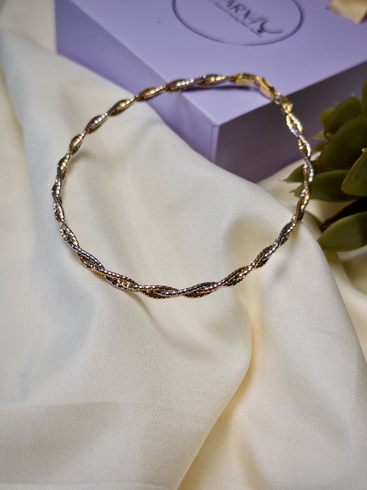 Twisted Gold anklet on a white fabric with a purple box in the background