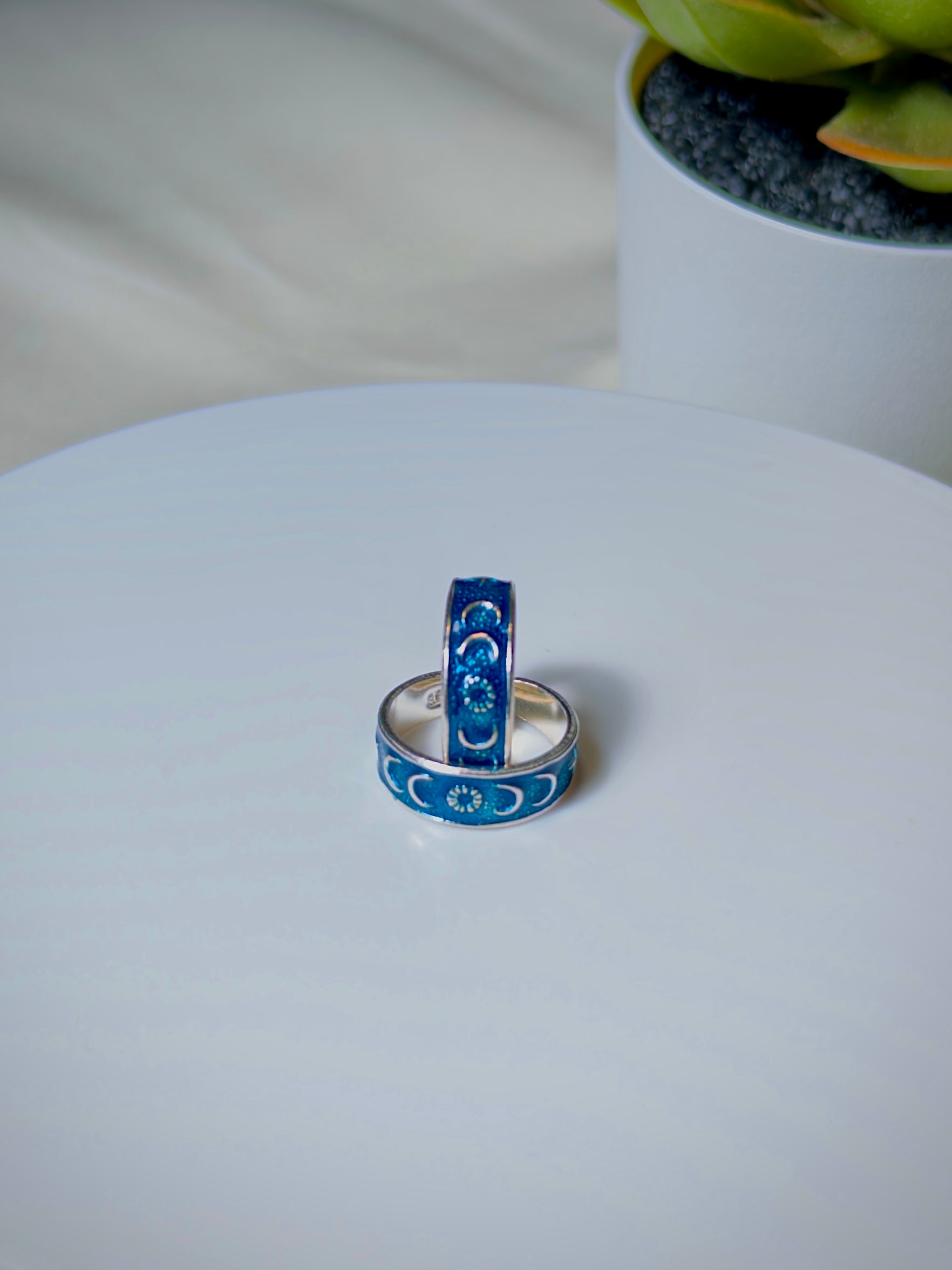 Two blue toe rings with moon designs on a white surface.