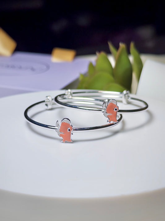 Silver baby kada with rhino charms on a white surface