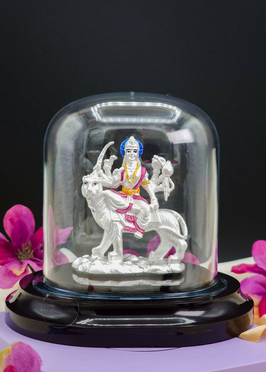 Statue of Ambe Mata Idol inside a glass dome with pink flowers in the background