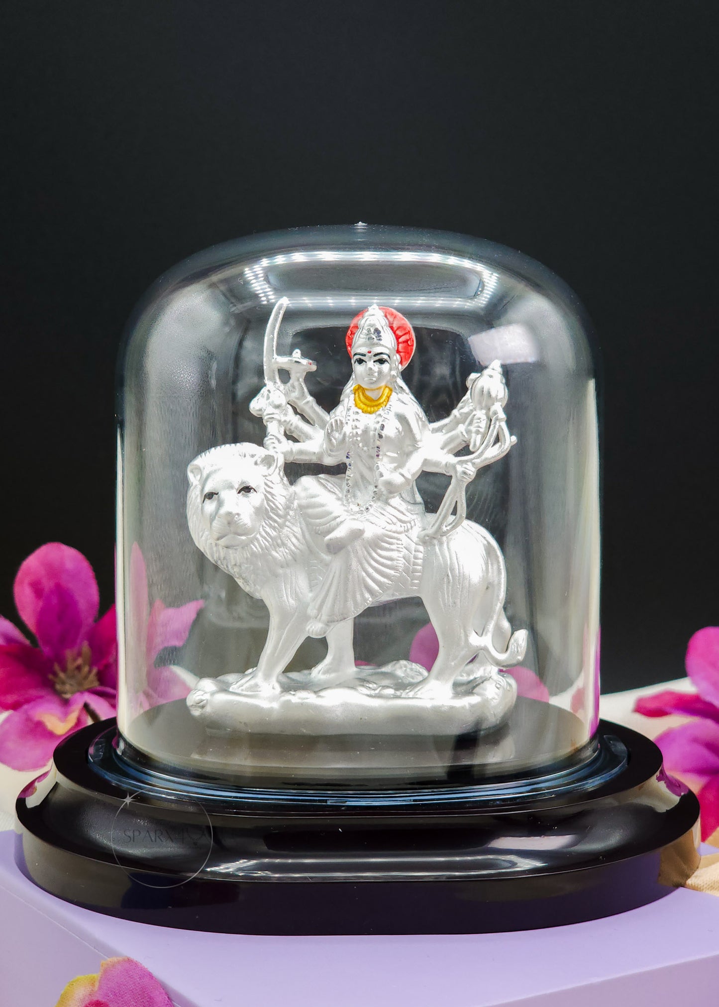 Durga Mata Idol inside a glass dome with flowers in the background