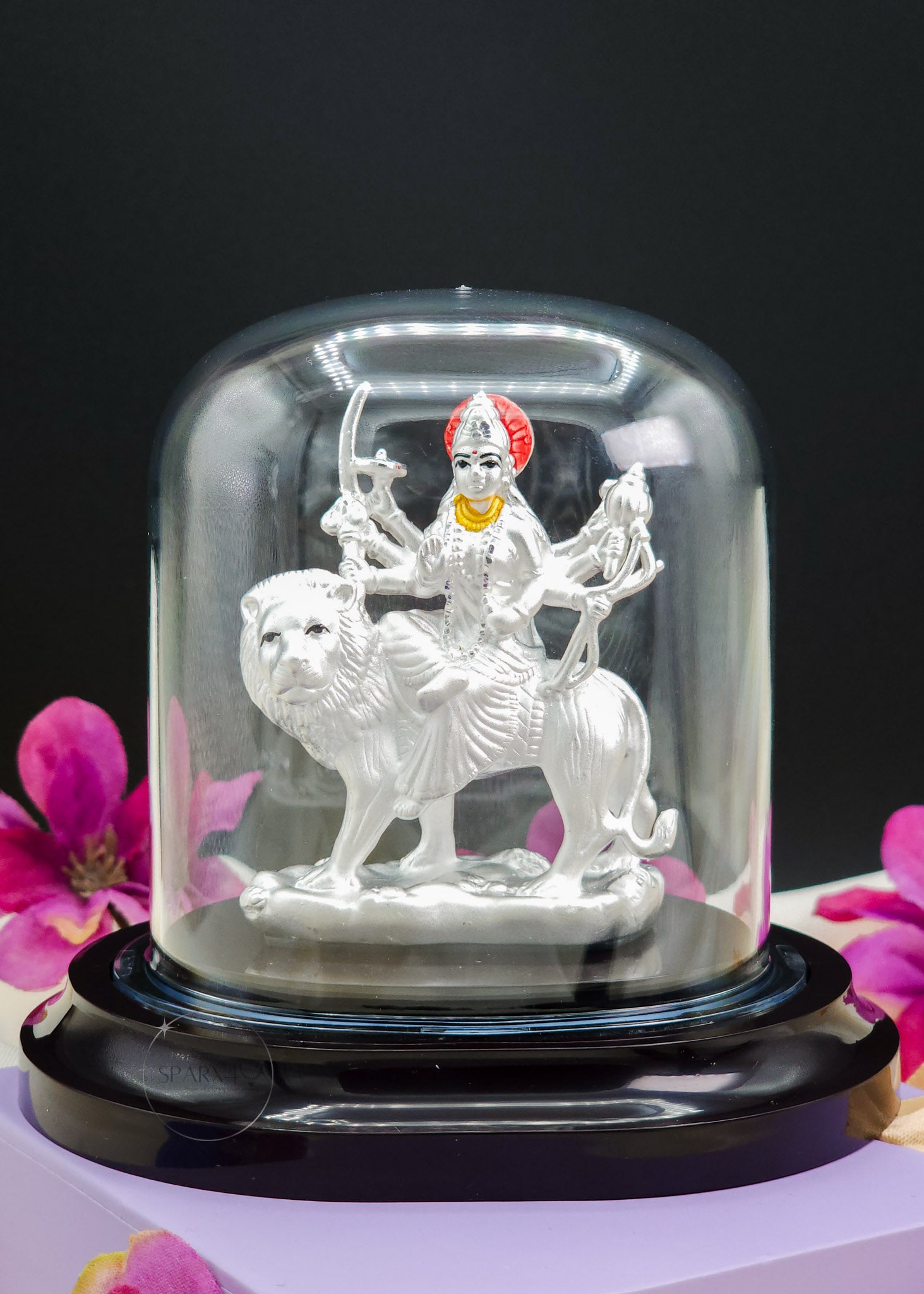 Durga Mata Idol inside a glass dome with flowers in the background