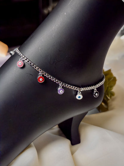 Silver anklet with colorful evil eye on a black mannequin foot.