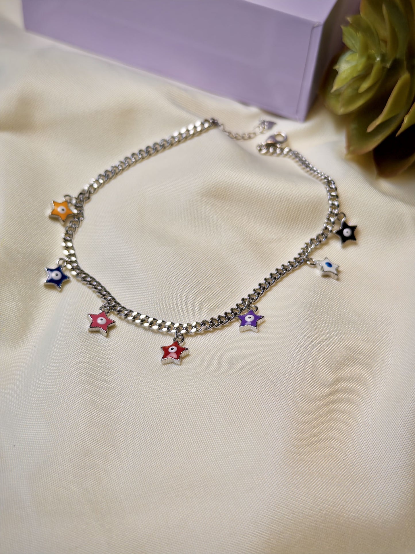 Silver bracelet with colorful star charms on a beige surface