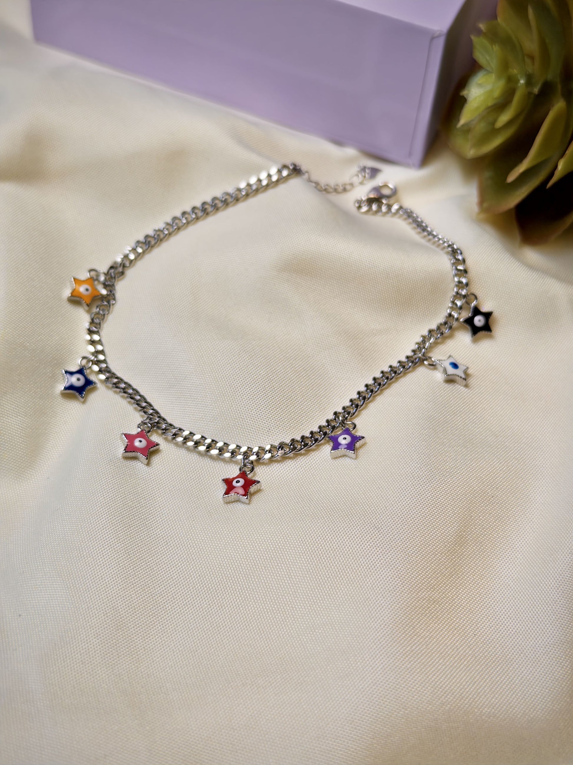 Silver bracelet with colorful star charms on a beige surface