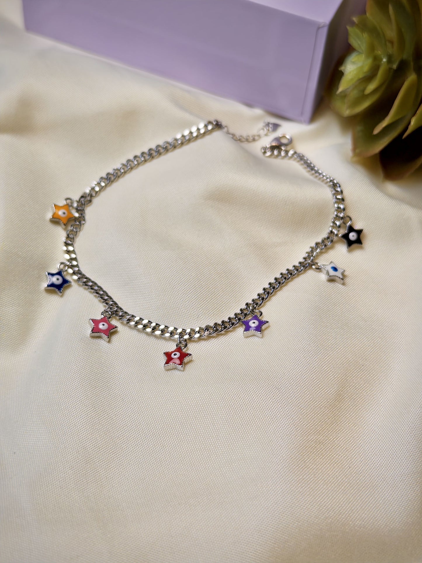 Silver bracelet with colorful star charms on a beige surface