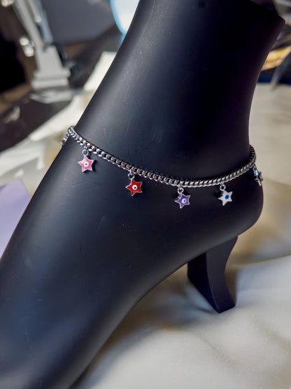 Ankle with multiple anklets featuring star-shaped charms on a dark surface.