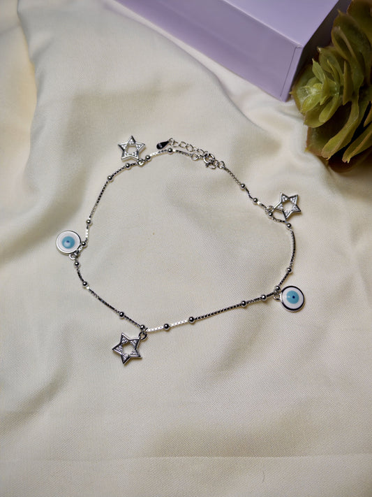 Silver bracelet with star and eye-shaped charms on a beige surface