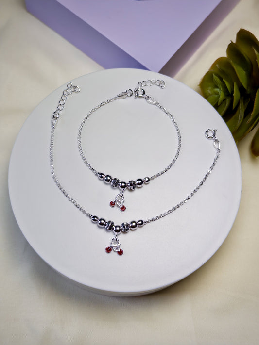 Kids silver anklets with red beads on a white plate