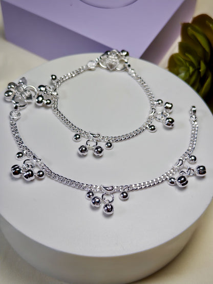 Kids silver anklets with beads on a white surface