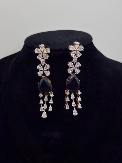 Pair of earrings with sapphire stones and diamond-like crystals on a black velvet stand.