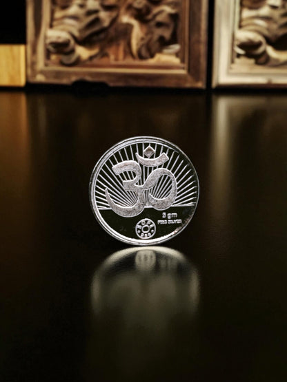 Silver coin with a Lakshmi Ganesh design on a reflective surface