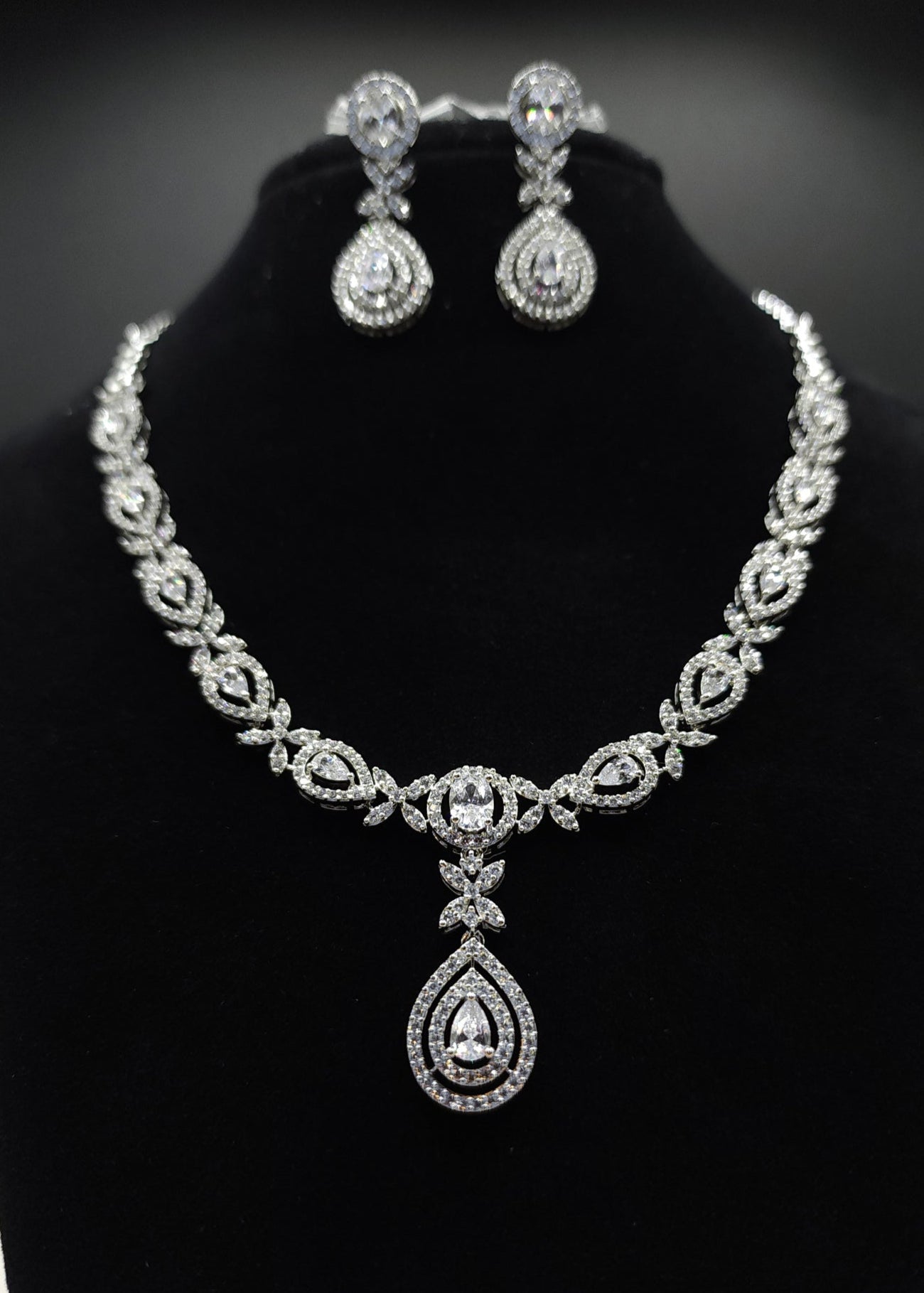 Silver necklace and earrings set on a black stand with 'SPARX4U' branding.