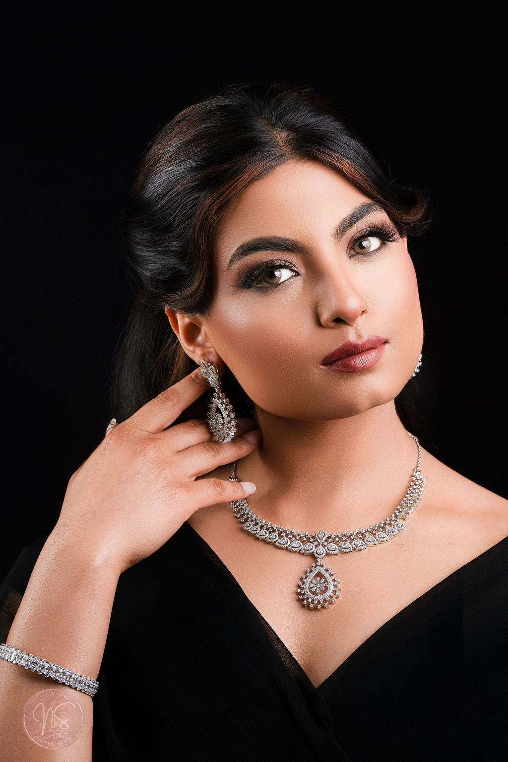 Woman wearing a diamond necklace and earrings on a black background
