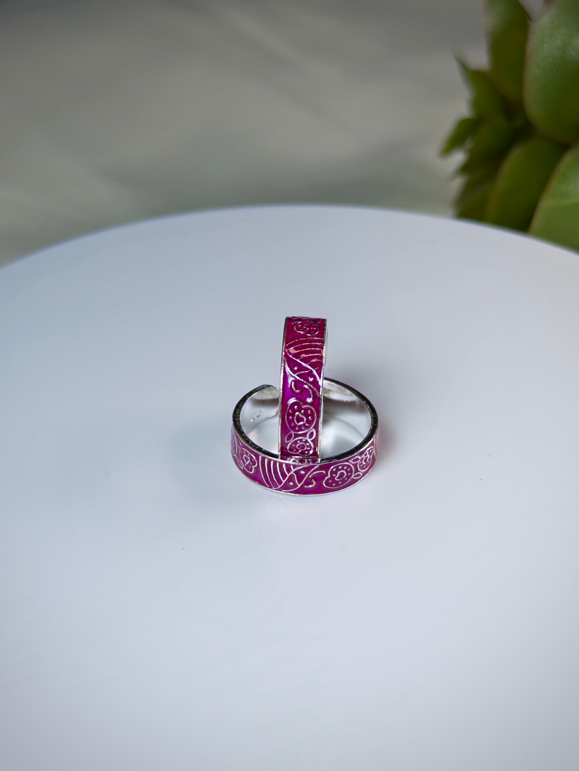 Two pink toe rings with silver bands on a white surface.