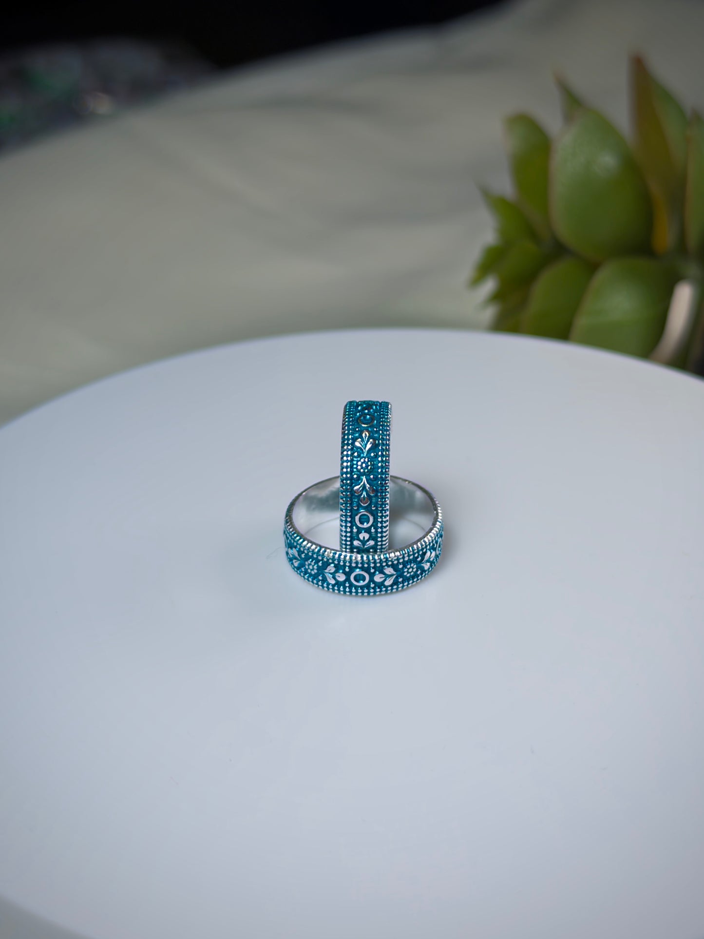 Two toe rings with blue and silver designs on a white surface.
