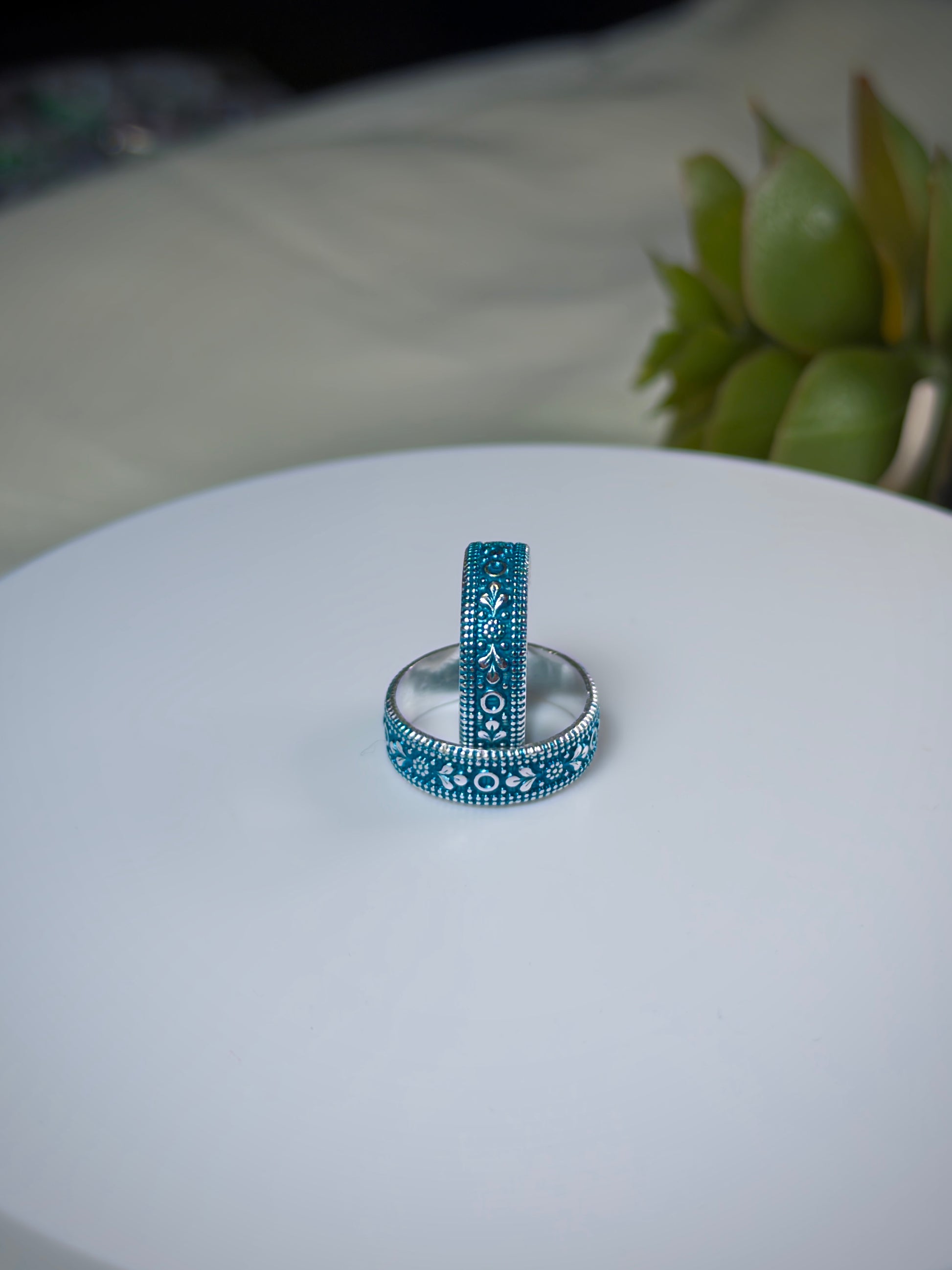 Two toe rings with blue and silver designs on a white surface.