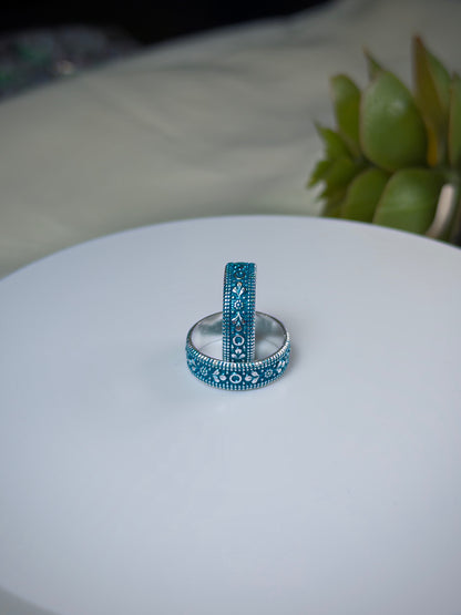 Two toe rings with blue and silver designs on a white surface.