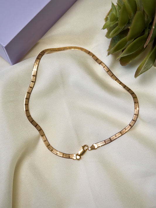 Rose Gold Anklet on a beige fabric surface with a plant in the background