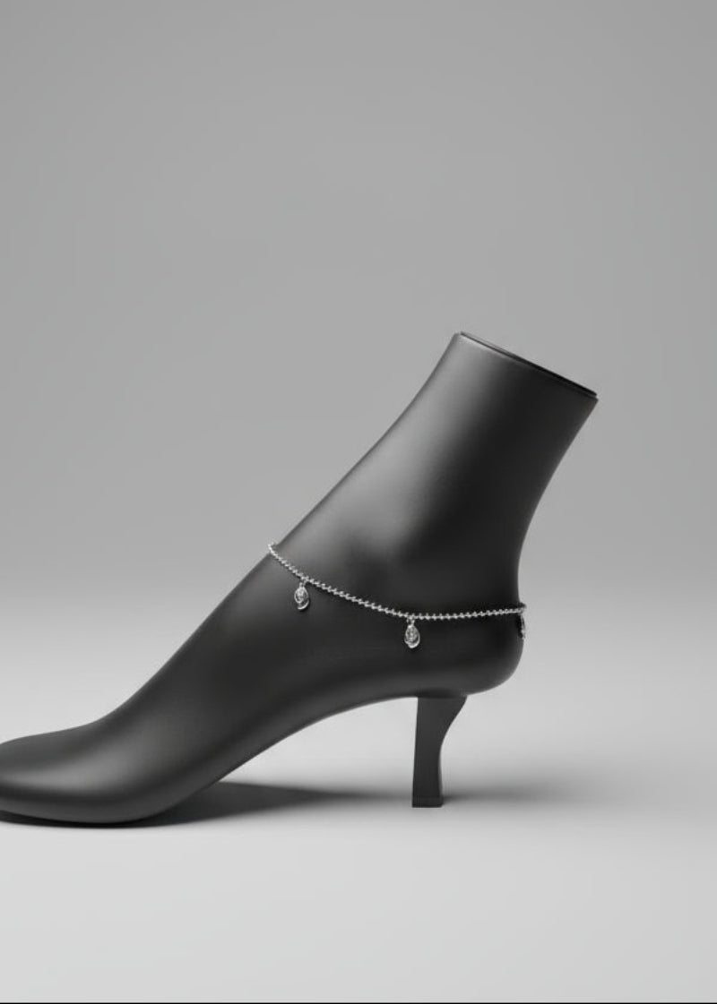 Silver anklet on a mannequin foot with a dark background