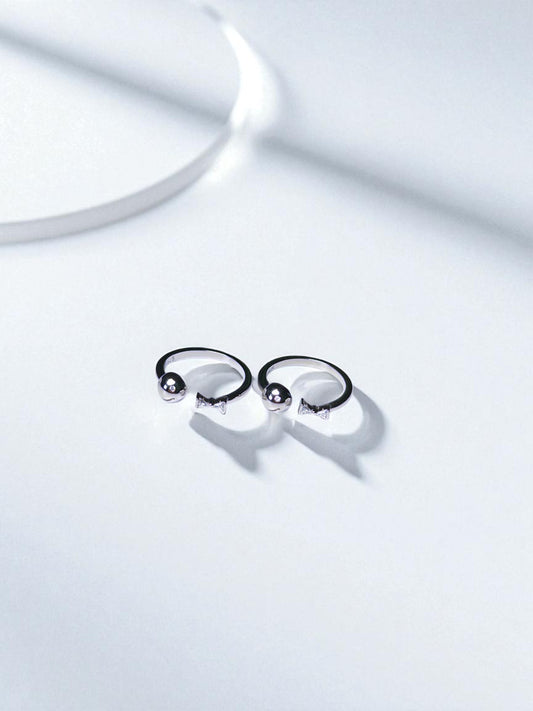 Pair of silver toe rings on a light gray background