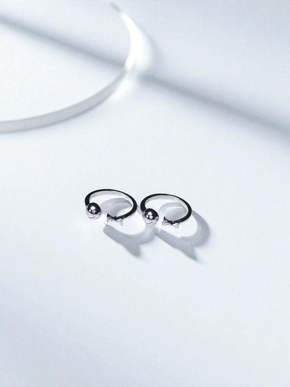 Pair of silver toe rings on a light gray background