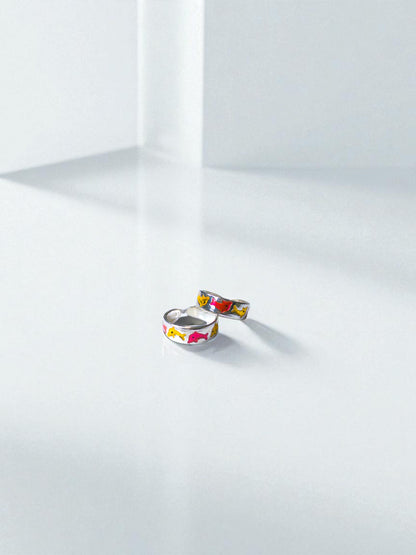 Two colorful toe rings on a white surface with a soft shadow