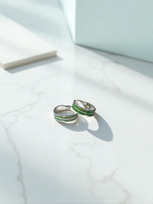Silver toe rings with green accents on a light marble surface