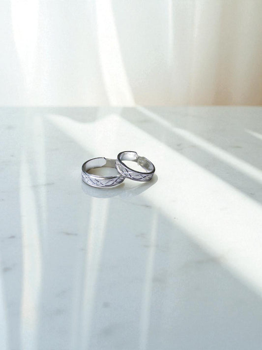 Two silver toe rings on a marble surface with soft lighting