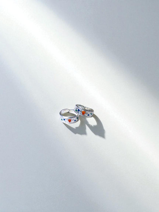 Two silver rings with colorful heart designs on a white background