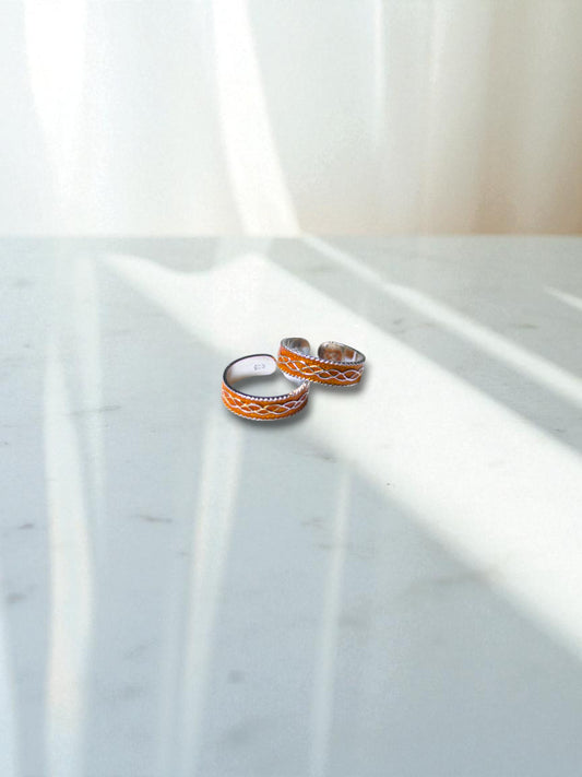Two silver toe rings on a marble surface with soft lighting