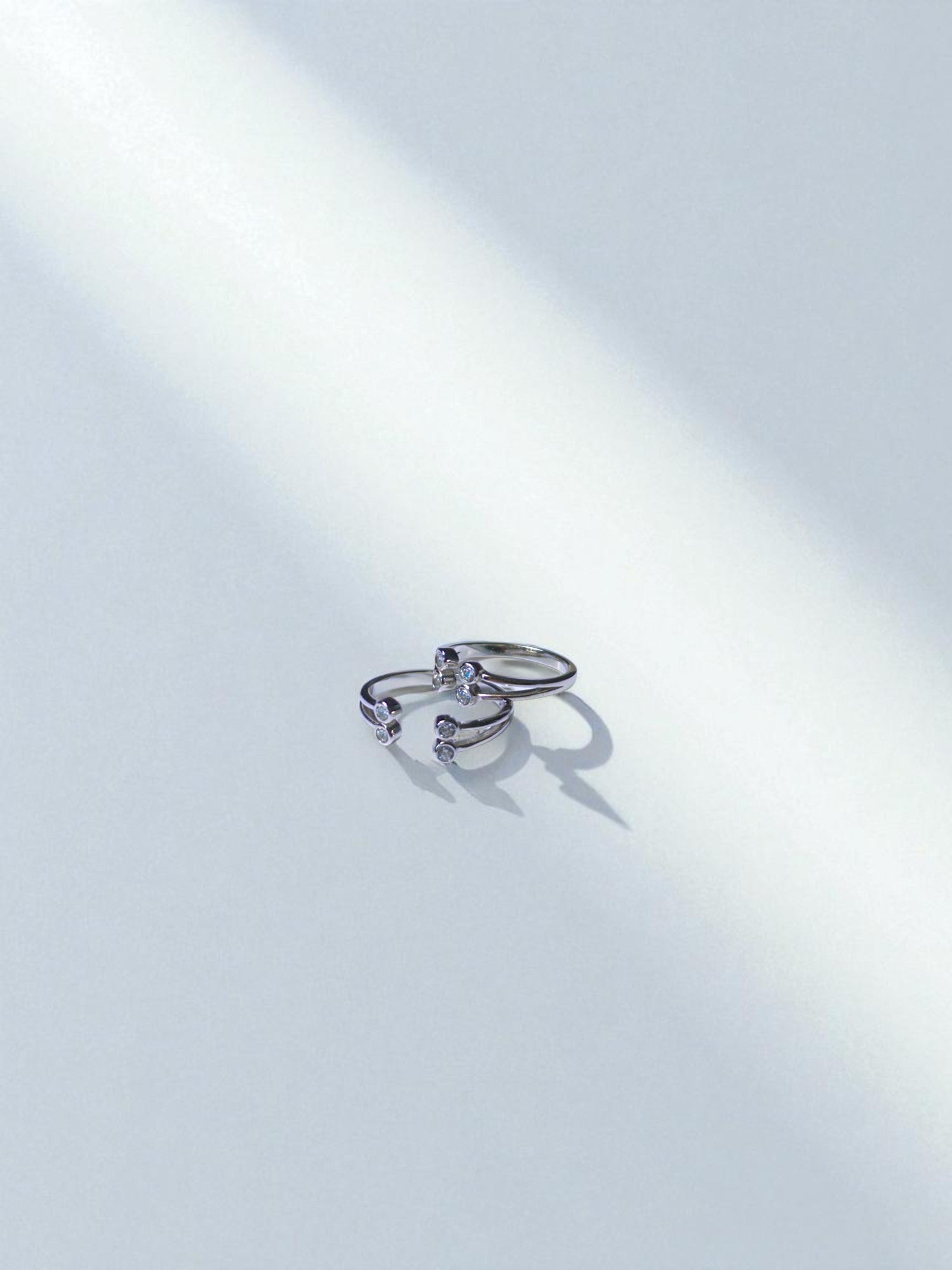 Two silver toe rings with small diamonds on a light gray background