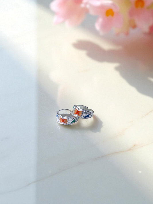 Silver toe rings with floral designs on a light surface