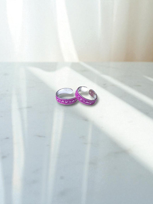 Two pink toe rings with intricate designs on a marble surface