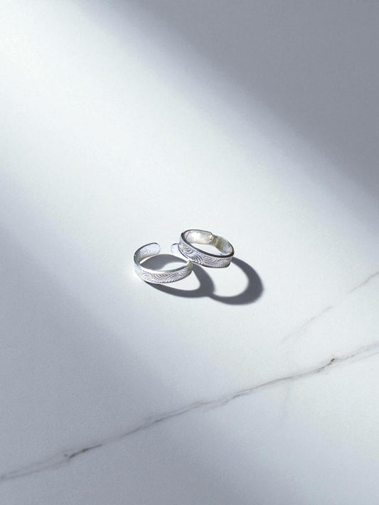 Two silver rings on a light gray marble surface