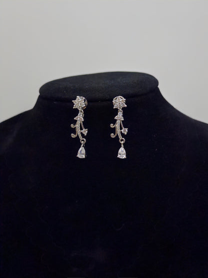 Pair of silver earrings on a black velvet stand with a plain background