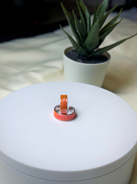 Two toe rings on a white surface with a plant in the background