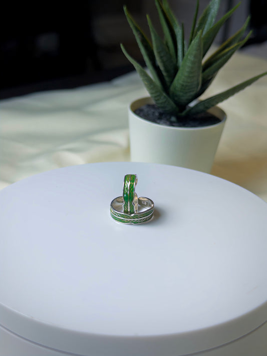 Two toe rings on a white surface with a plant in the background