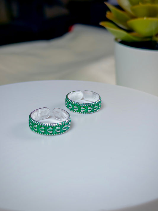 Silver rings with green patterns on a white surface