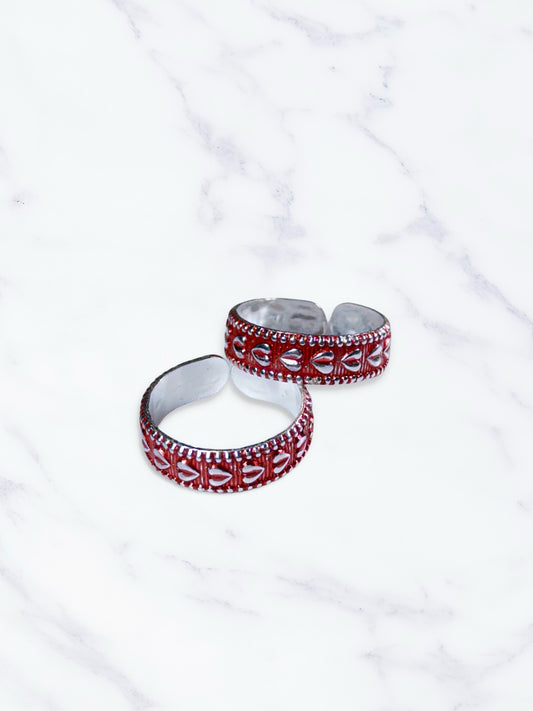 Two red and silver toe rings on a white marble surface